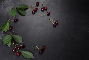 plato de cerezas dulces frescas con hojas en gotas de agua foto