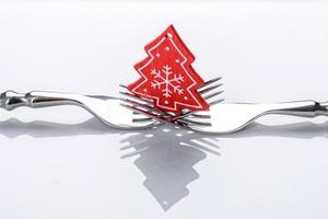 A small Christmas tree decoration on two forks on a white background