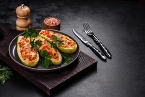 Baked stuffed zucchini boats with minced chicken mushrooms and vegetables with cheese photo