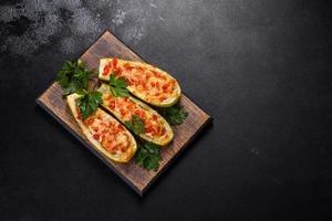 Baked stuffed zucchini boats with minced chicken mushrooms and vegetables with cheese photo