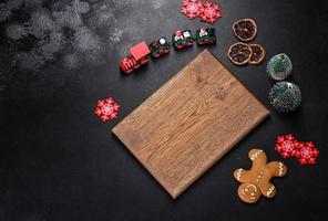 Christmas homemade gingerbread cookies, spices and cutting board on dark background photo