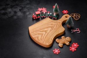 Christmas homemade gingerbread cookies, spices and cutting board on dark background photo