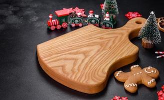Christmas homemade gingerbread cookies, spices and cutting board on dark background photo