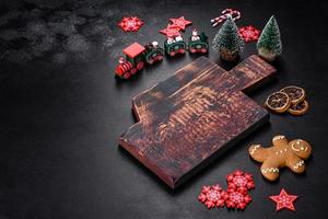 Christmas homemade gingerbread cookies, spices and cutting board on dark background photo