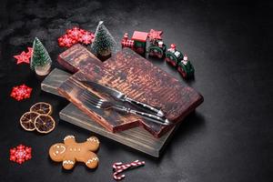 Christmas homemade gingerbread cookies, spices and cutting board on dark background photo