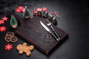 Christmas homemade gingerbread cookies, spices and cutting board on dark background photo
