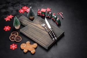 Christmas homemade gingerbread cookies, spices and cutting board on dark background photo