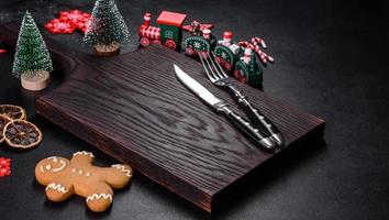 Christmas homemade gingerbread cookies, spices and cutting board on dark background photo
