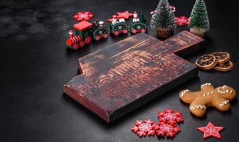 Christmas homemade gingerbread cookies, spices and cutting board on dark background photo
