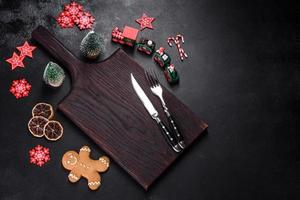 Christmas homemade gingerbread cookies, spices and cutting board on dark background photo