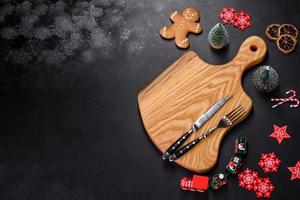 Christmas homemade gingerbread cookies, spices and cutting board on dark background photo