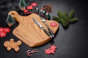 Christmas homemade gingerbread cookies, spices and cutting board on dark background photo