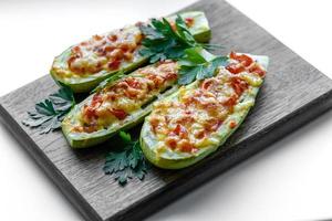 Baked stuffed zucchini boats with minced chicken mushrooms and vegetables with cheese photo