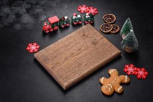 Christmas homemade gingerbread cookies, spices and cutting board on dark background photo