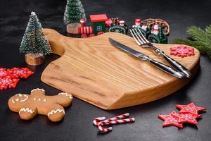 Christmas homemade gingerbread cookies, spices and cutting board on dark background photo