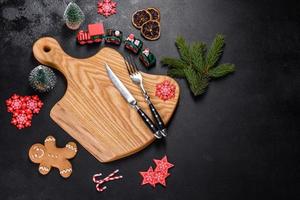Christmas homemade gingerbread cookies, spices and cutting board on dark background photo