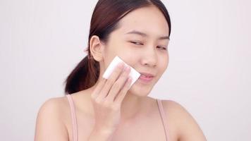 Happy Asian girl using cotton pad applying facial wipe on her face, removing makeup. video