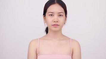 asiatisk flicka med naturlig makeup tittar upp på vit bakgrund. video