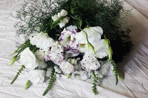 White bouquet of flowers on a white background, against the background of bed linen, a bouquet of green color, background, white beautiful flowers photo
