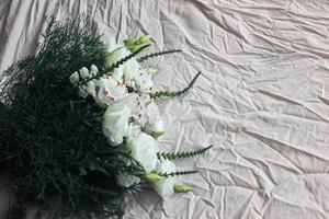 White bouquet of flowers on a white background, against the background of bed linen, a bouquet of green color, background, white beautiful flowers photo