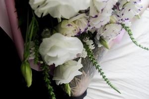 White flowers, bouquet on a white sheet, black leg tattoo photo