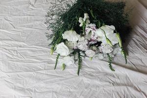 White bouquet of flowers on a white background, against the background of bed linen, a bouquet of green color, background, white beautiful flowers photo