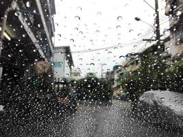 gotas de agua en una ventana bajo la lluvia. vista del coche en la calle. foto