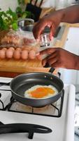 Photo of black hands which are salting a fried egg