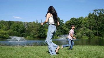 moeder en zoon kind blij rennen samen ronddraaien in een zomerpark video