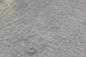 pattern of brown river sand with trail marks of water wave photo