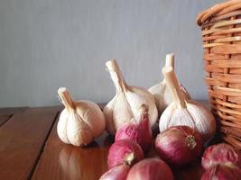 Ripe and raw organic onion and garlic on wooden background photo