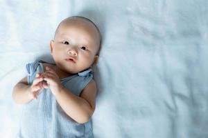bebé asiático tendido de la mano sobre una alfombra azul. foto
