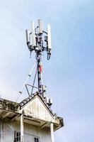 Communication tower with antennas on the top of building and bright blue sky background. photo