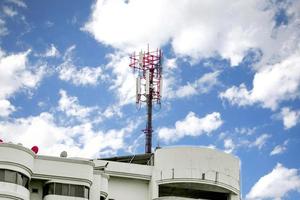 torre de comunicación con antenas en la parte superior del edificio y cielo azul brillante con fondo de nubes. foto