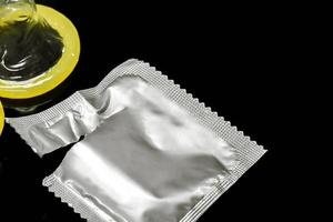 Closeup condom and opened package isolate on black background photo