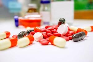 Close up of Red pill medicines and capsule place on white table with ampule blurry background. photo