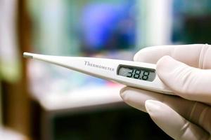 Closeup Medical thermometer in hands of doctor on blurry background.. photo