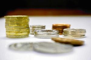 The new one pound as vertical and stack of British currency coins on white table and black ground. photo