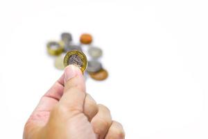 Image of hand picking up a British currency coins from stack on white background. Make with paths. photo