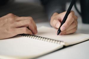 left handed man writes in a notebook on the table photo