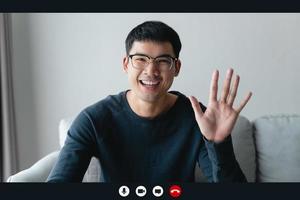Portrait happy man working at home by video conference meeting waving hand, talking and looking at camera. greeting family or friends photo