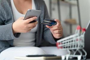 Woman holding credit card and using smartphone for online shopping, internet banking, e-commerce, spending money. photo