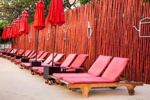 sombrilla roja y sillas de piscina al amanecer alrededor de la piscina al aire libre. foto