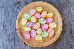 Colorful gummy candy on wooden dish and on wooden background. Copy space background and texture photo