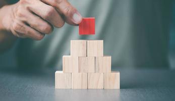 The young man was putting the red wooden blocks on top of the other wooden blocks. photo