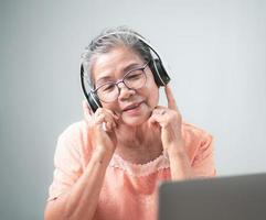 old senior woman happily using headphones photo