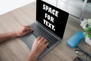 The laptop computer is placed on a wooden table photo