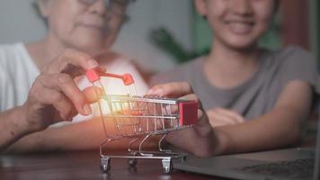 Grandma and granddaughter hold a shopping cart lying on the table, photo