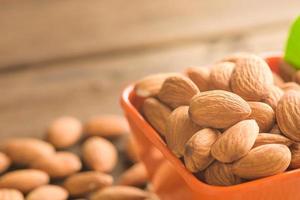 Almonds in an orange cup and placed on an old wooden table photo