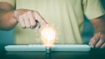 The young man put his hand on the light bulb on the table. photo